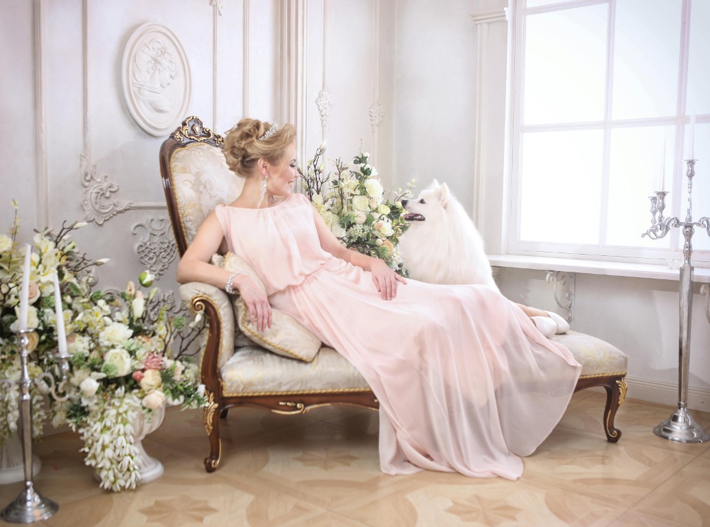 Bride in a pink gown sitting beside a white dog